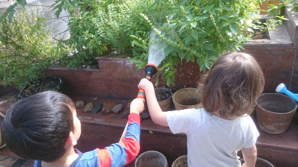 Watering with team work too! One child is waiting at the faucet, and other two were holding the hose. 